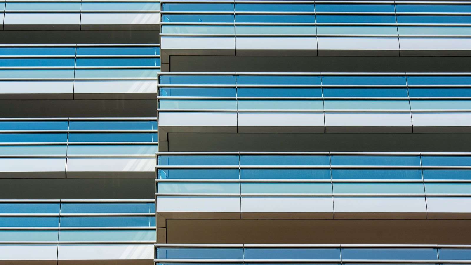 Detail of a modern office building facade with horizontal glass and metal banding.